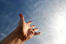a left hand reaching towards the sun