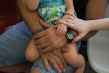 father holding toddler girl on lap while mom rests her hand on the toddler's knee